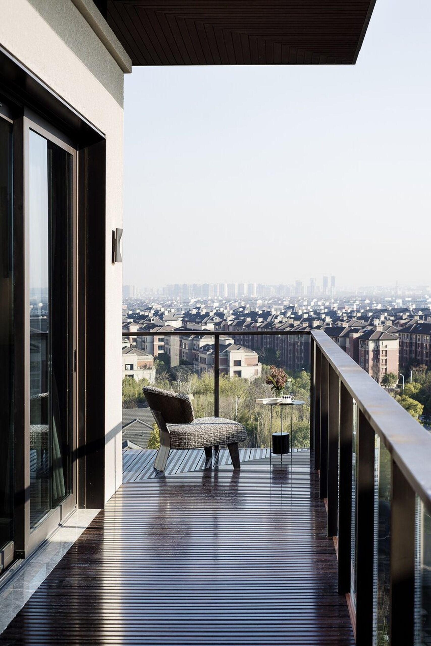 Balcone moderno con pavimento in legno lucido, sedia elegante e vista panoramica sulla città